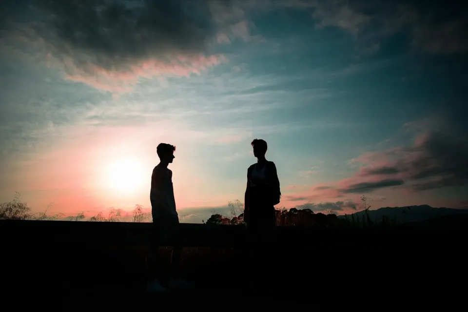 Deux jeunes en conversation, silhouettes au coucher du soleil