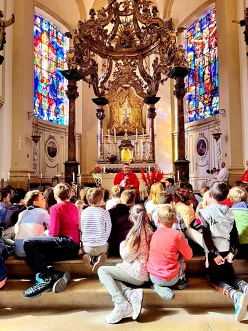 L'assemblée réunie dans l'église devant l'autel et ses vitraux, pendant la messe